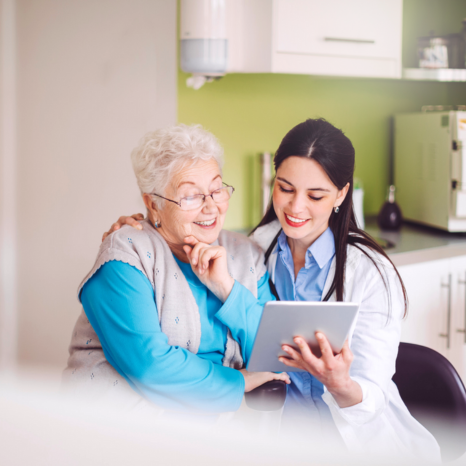 A doctor and patient smiling while looking at a tablet together