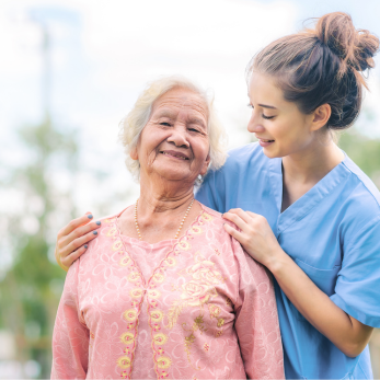 A Doctor, dressed in a light blue uniform, assists one of the elderly individuals with a warm smile.